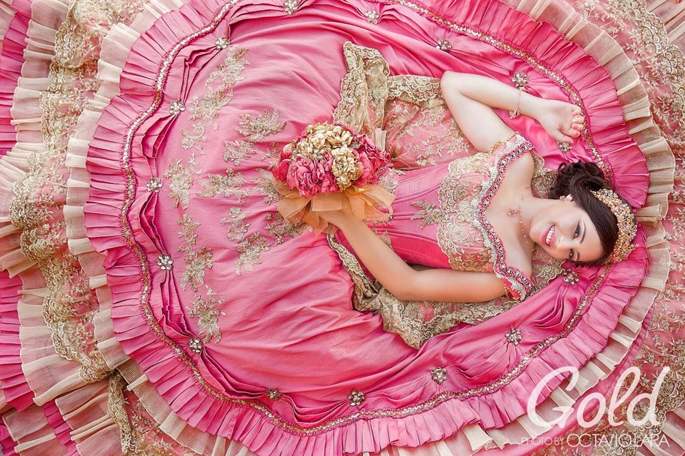 Quinceañera recostada entre los pliegues de su vestido rosa